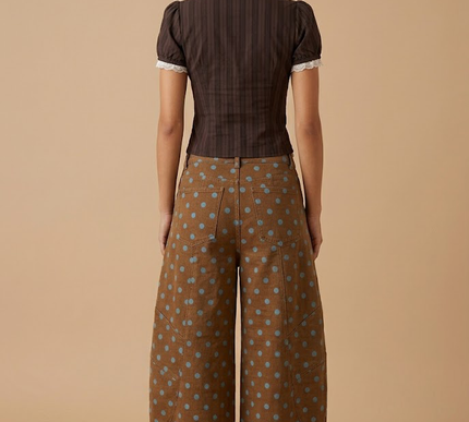 Person wearing a brown patterned outfit on a beige background