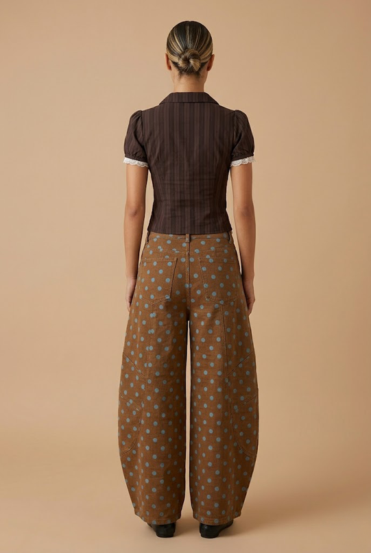 Person wearing a brown patterned outfit on a beige background