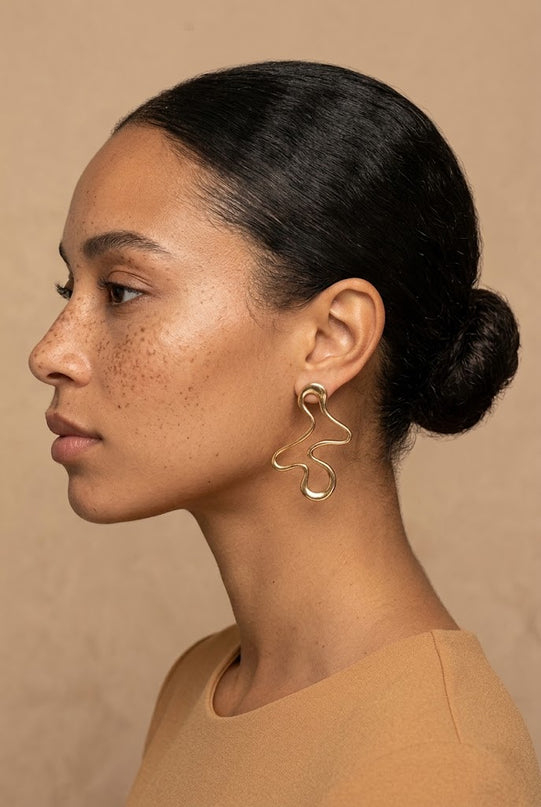 Sculptural gold-tone statement earrings with an irregular hollowed shape, ornate jewellery for fall 2026 evening dressing